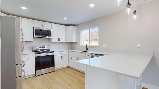 kitchen featuring stainless steel appliances, white cabinetry, hanging light fixtures, and sink