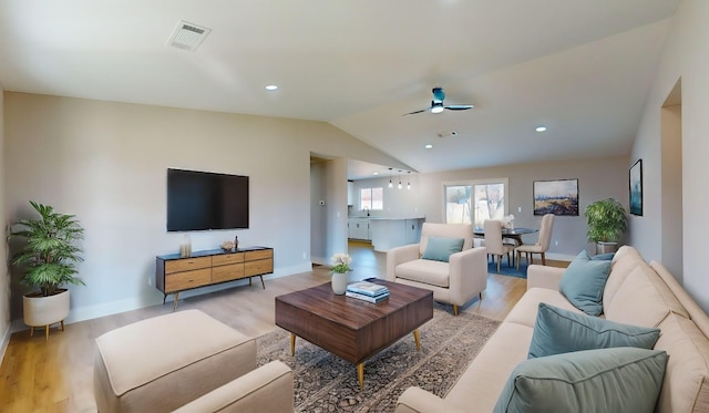 living room with ceiling fan, light wood-type flooring, sink, and vaulted ceiling