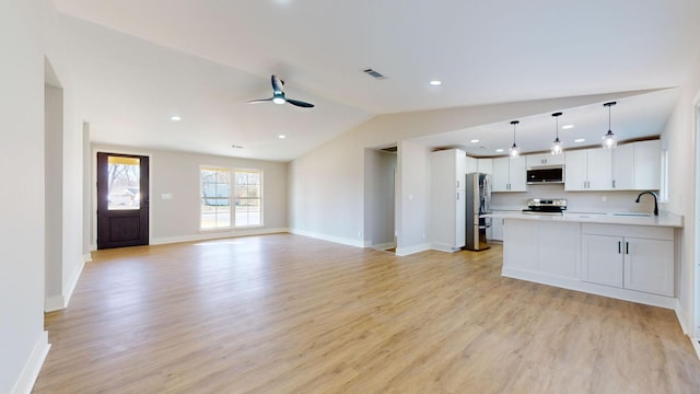 kitchen featuring ceiling fan, hanging light fixtures, stainless steel appliances, vaulted ceiling, and white cabinets