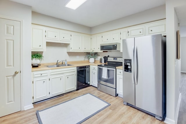 kitchen featuring sink, white cabinets, stainless steel appliances, and light wood-type flooring