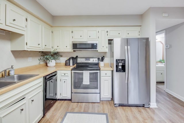 kitchen with tasteful backsplash, stainless steel appliances, sink, light hardwood / wood-style flooring, and white cabinetry