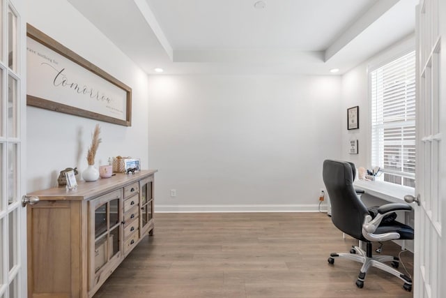 office space featuring french doors, light wood-type flooring, and a raised ceiling