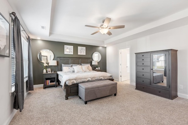 carpeted bedroom featuring a tray ceiling and ceiling fan