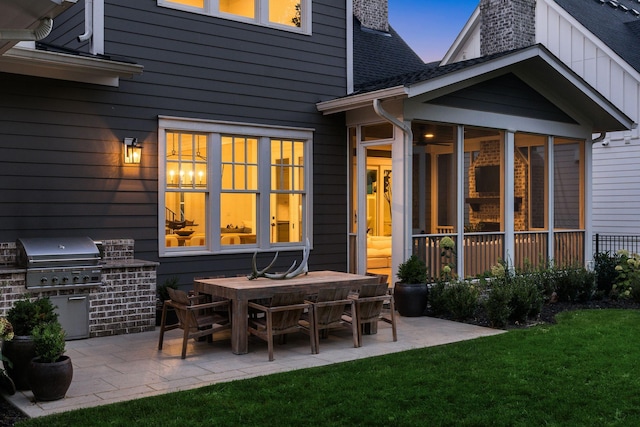 back house at dusk featuring area for grilling, a sunroom, a yard, and a patio