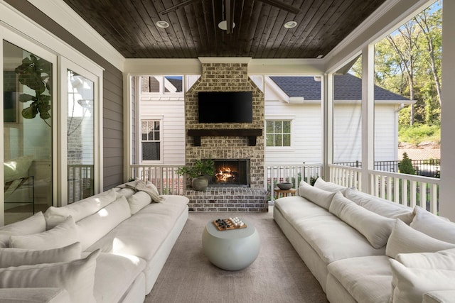 living room featuring a healthy amount of sunlight, wood ceiling, and an outdoor brick fireplace