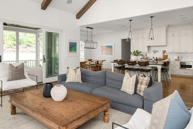 living room with beamed ceiling, high vaulted ceiling, and light hardwood / wood-style flooring