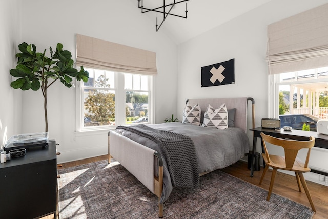 bedroom with dark hardwood / wood-style floors, vaulted ceiling, and a notable chandelier