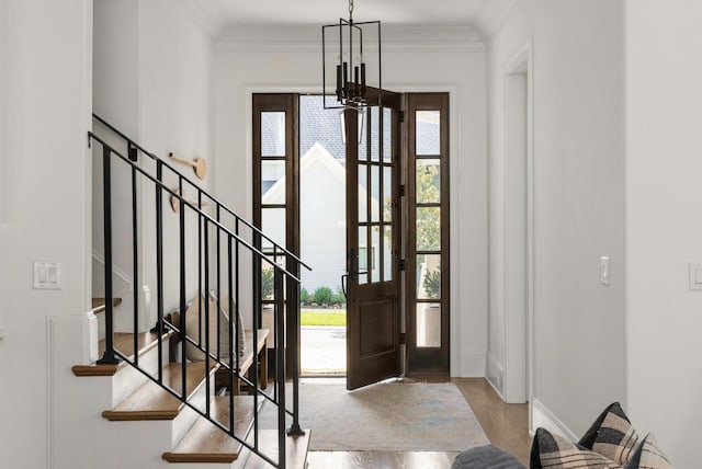 foyer entrance featuring light hardwood / wood-style flooring, a healthy amount of sunlight, a notable chandelier, and ornamental molding