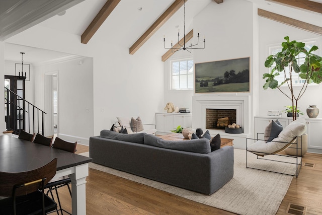 living room featuring lofted ceiling with beams, wood-type flooring, and ornamental molding