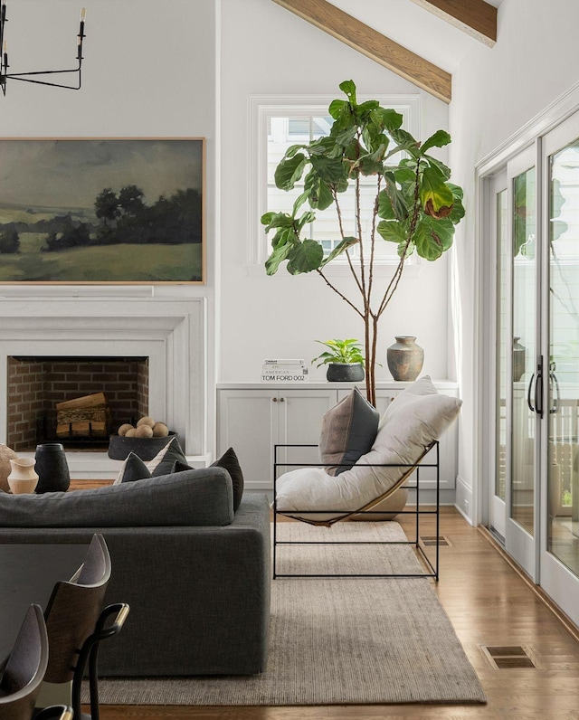 living area with a chandelier, hardwood / wood-style floors, and lofted ceiling with beams