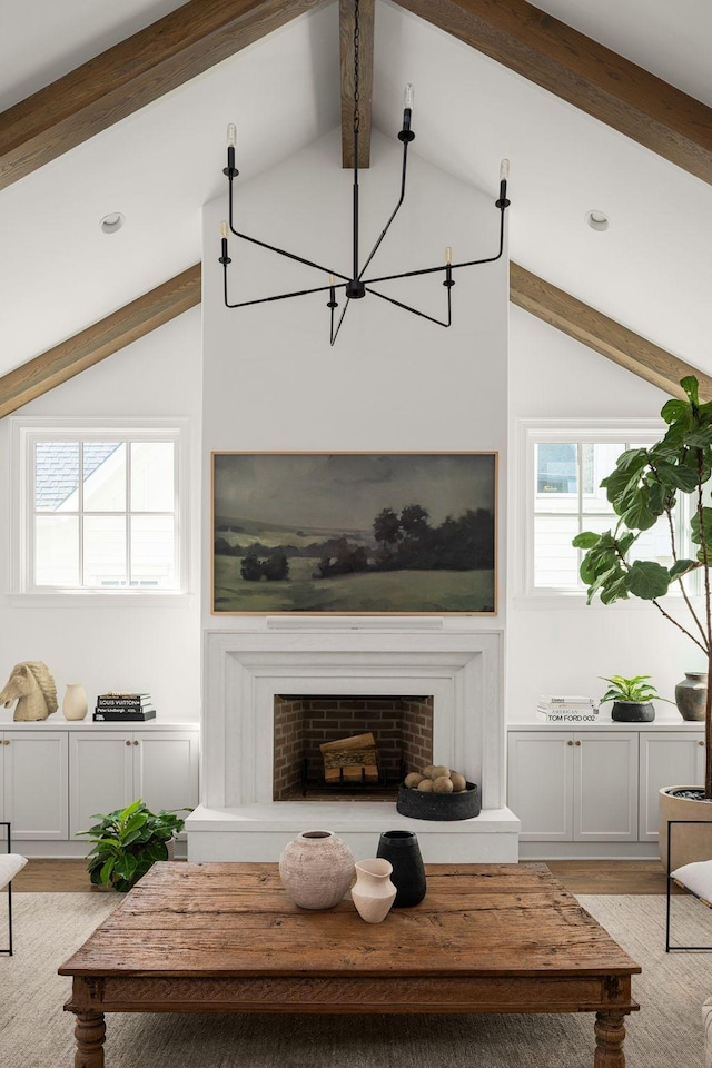 living room featuring vaulted ceiling with beams, an inviting chandelier, and light wood-type flooring