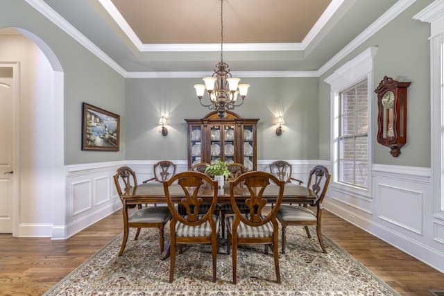 dining room featuring an inviting chandelier, wood-type flooring, ornamental molding, and a raised ceiling