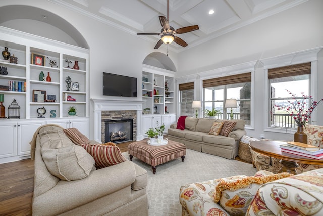 living room featuring crown molding, a high ceiling, coffered ceiling, dark hardwood / wood-style flooring, and a stone fireplace