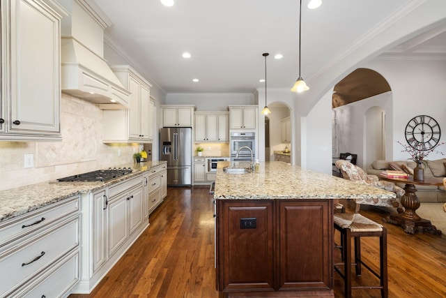 kitchen with sink, hanging light fixtures, a kitchen breakfast bar, an island with sink, and stainless steel appliances