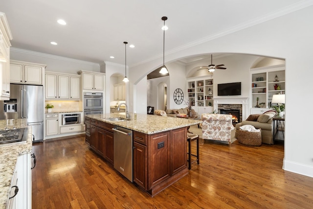 kitchen with appliances with stainless steel finishes, pendant lighting, sink, a breakfast bar area, and a center island with sink