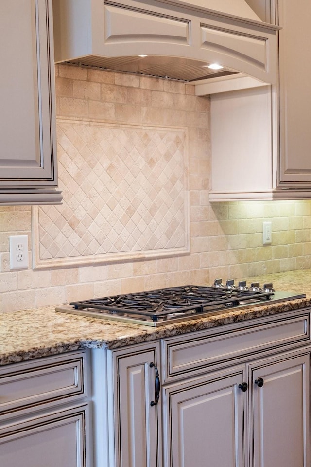 kitchen with stone countertops, backsplash, and stainless steel gas cooktop