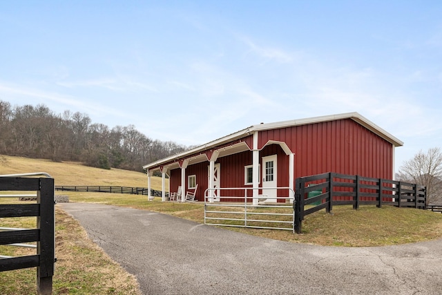 view of front of house featuring an outdoor structure and a rural view