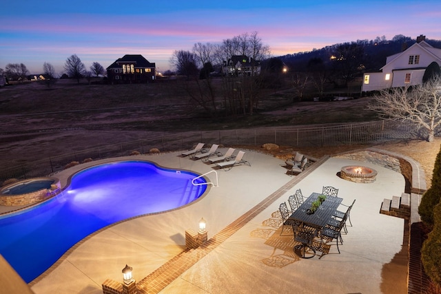 pool at dusk featuring a patio and a fire pit