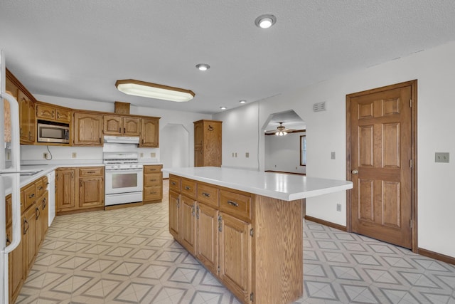 kitchen with ceiling fan, a kitchen island, white appliances, and a textured ceiling