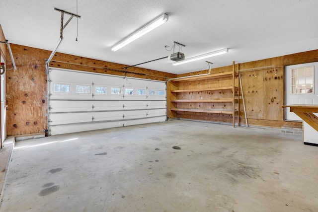 garage featuring a garage door opener and wood walls