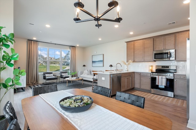 kitchen featuring decorative backsplash, stainless steel appliances, sink, wood-type flooring, and a chandelier