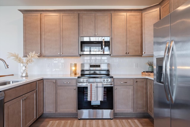 kitchen with decorative backsplash, light hardwood / wood-style floors, sink, and stainless steel appliances