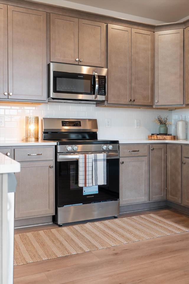 kitchen featuring appliances with stainless steel finishes, light wood-type flooring, and backsplash