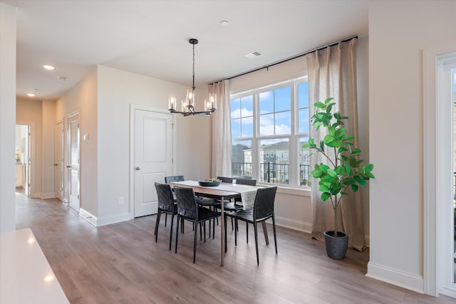 dining area with an inviting chandelier and light hardwood / wood-style flooring