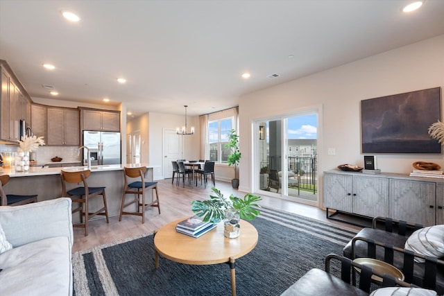 living room with light hardwood / wood-style floors and an inviting chandelier