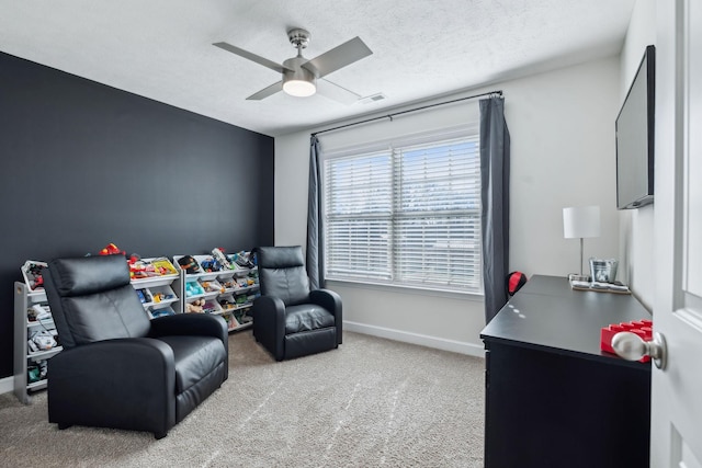 living area featuring a healthy amount of sunlight, ceiling fan, light colored carpet, and a textured ceiling