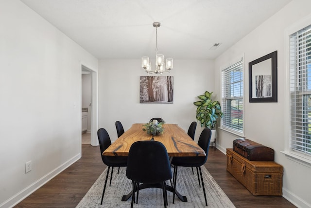 dining space featuring dark hardwood / wood-style flooring and an inviting chandelier