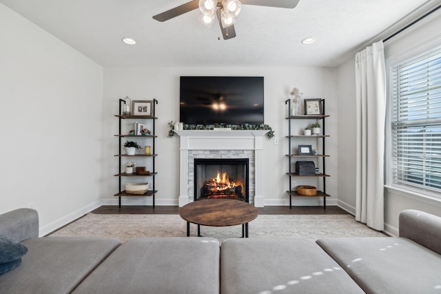 living room featuring ceiling fan, light wood-type flooring, and a fireplace