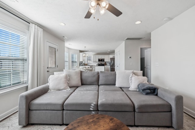 living room with ceiling fan with notable chandelier and a healthy amount of sunlight