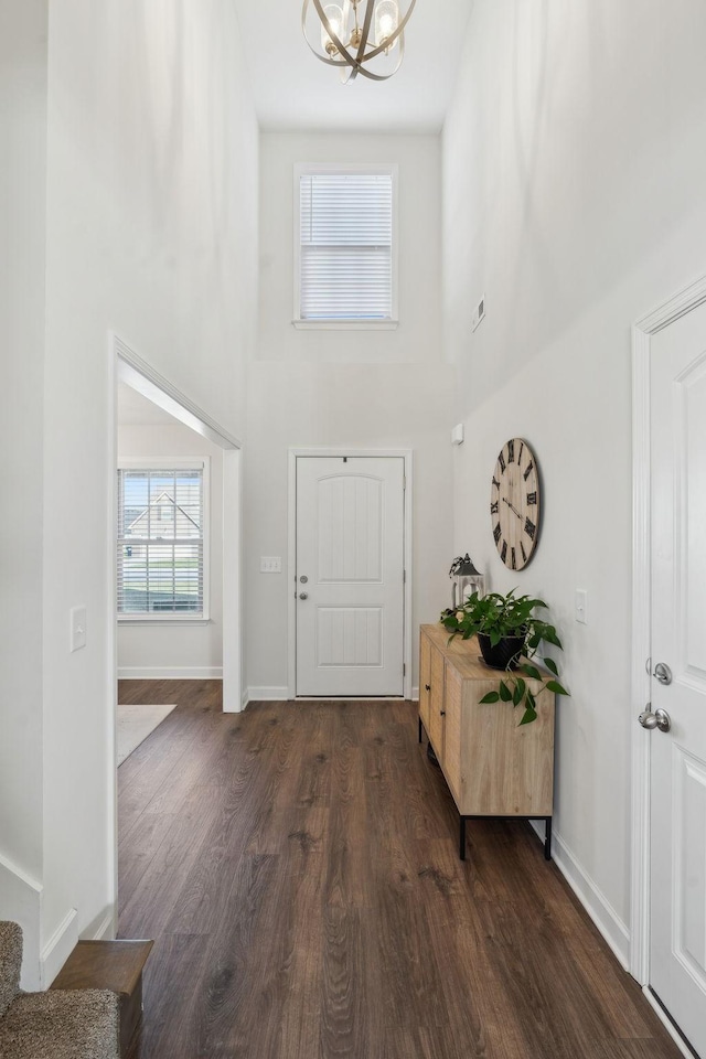 entrance foyer with dark hardwood / wood-style flooring, a high ceiling, and an inviting chandelier