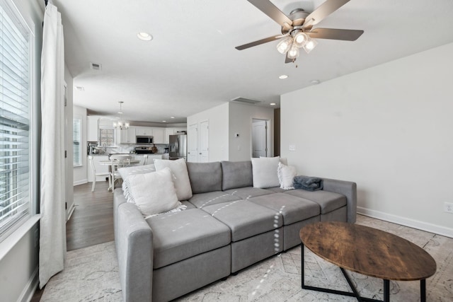 living room featuring ceiling fan with notable chandelier and light hardwood / wood-style flooring