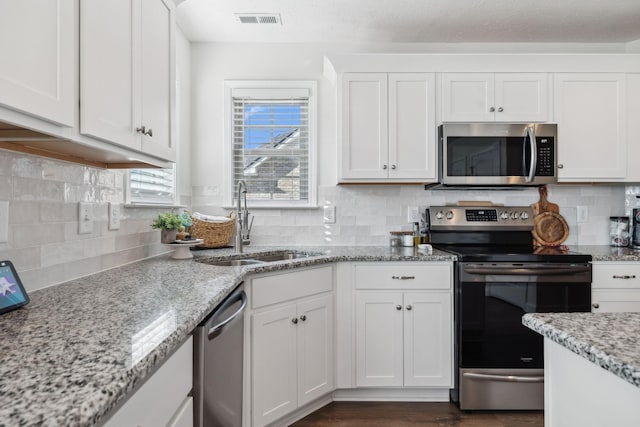 kitchen featuring white cabinets, sink, decorative backsplash, light stone countertops, and stainless steel appliances