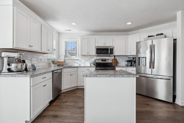 kitchen with white cabinets, a kitchen island, stainless steel appliances, and dark hardwood / wood-style floors