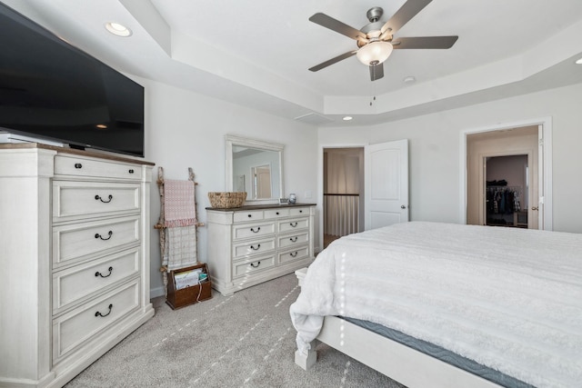 carpeted bedroom featuring a raised ceiling and ceiling fan