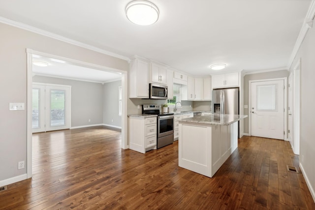 kitchen with white cabinetry, light stone countertops, dark hardwood / wood-style flooring, a kitchen island, and appliances with stainless steel finishes