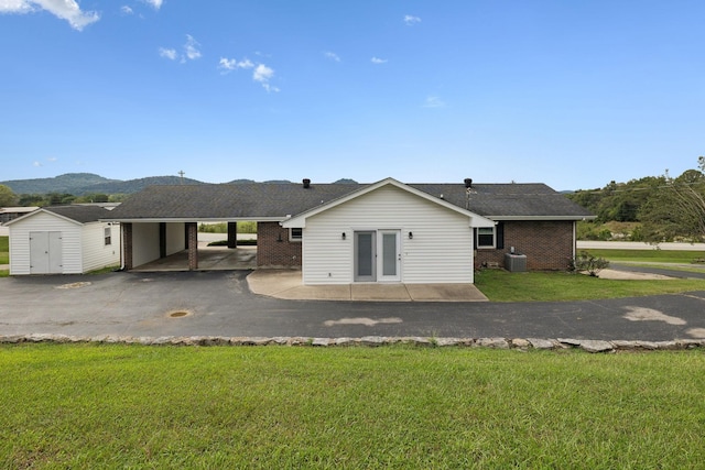 rear view of property with a mountain view, a carport, and a lawn