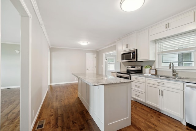 kitchen with white cabinetry, sink, a center island, stainless steel appliances, and ornamental molding