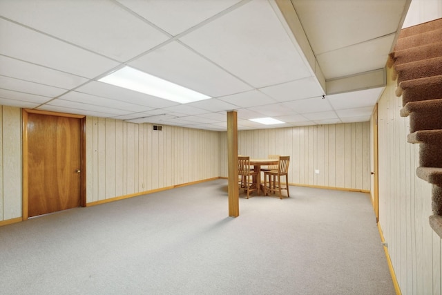 basement with a paneled ceiling and light colored carpet