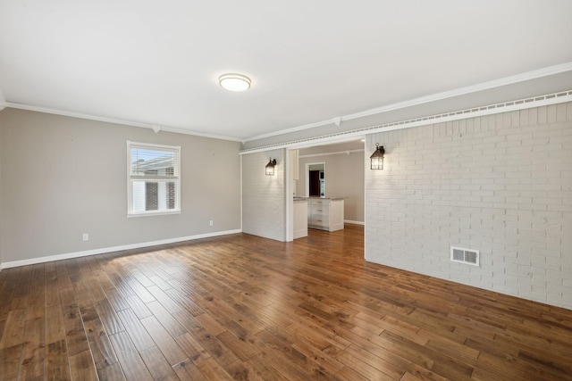 empty room with ornamental molding, dark wood-type flooring, and brick wall