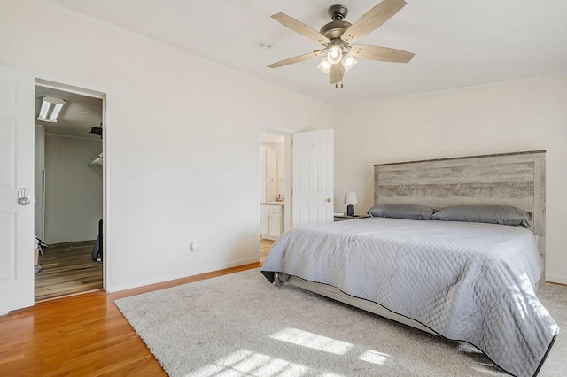 bedroom featuring ceiling fan, wood-type flooring, and ensuite bath