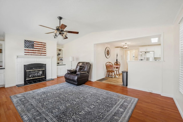 living room featuring hardwood / wood-style flooring, ceiling fan, lofted ceiling, and a fireplace