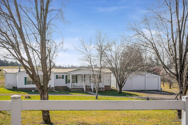 view of front of house featuring a porch, a garage, a front lawn, and an outdoor structure