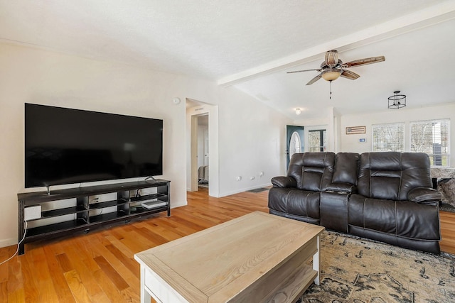 living room featuring hardwood / wood-style floors, vaulted ceiling with beams, and ceiling fan