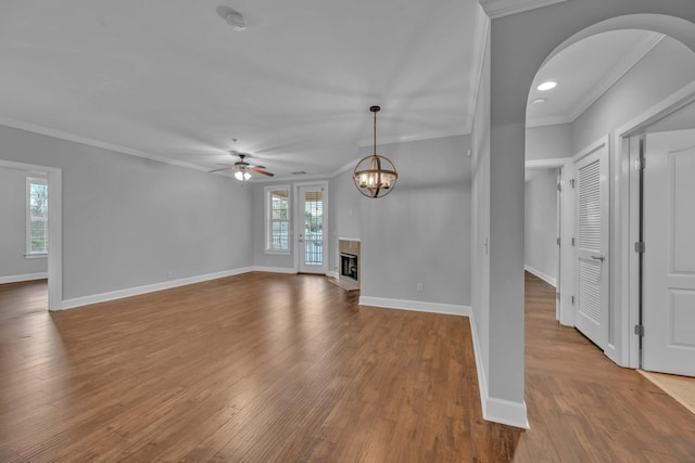 unfurnished living room featuring hardwood / wood-style floors, ceiling fan with notable chandelier, and ornamental molding