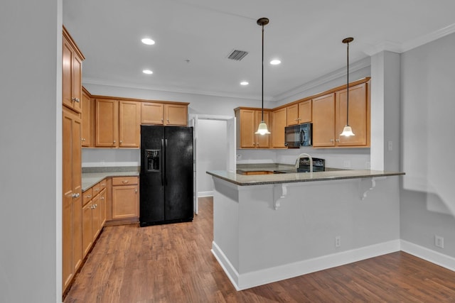 kitchen featuring hanging light fixtures, a kitchen breakfast bar, kitchen peninsula, crown molding, and black appliances