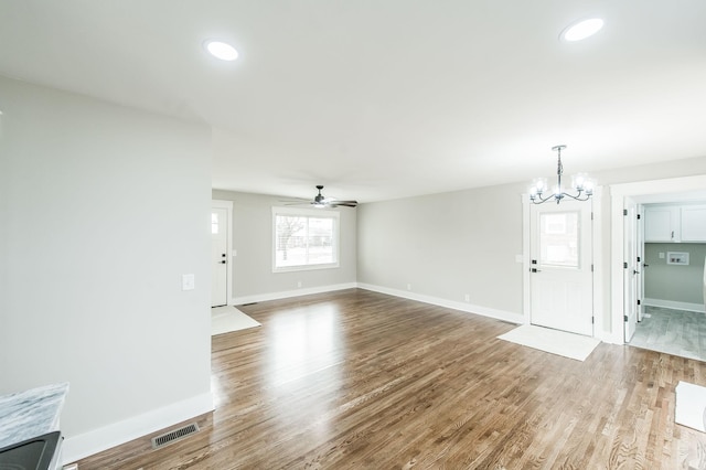 unfurnished living room with ceiling fan with notable chandelier and hardwood / wood-style flooring